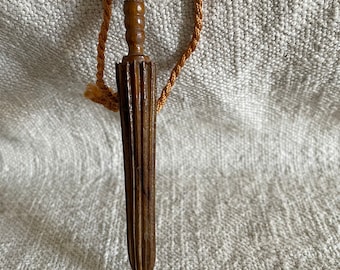 May include: A wooden, carved, umbrella-shaped, decorative object with a brown cord attached to the top.