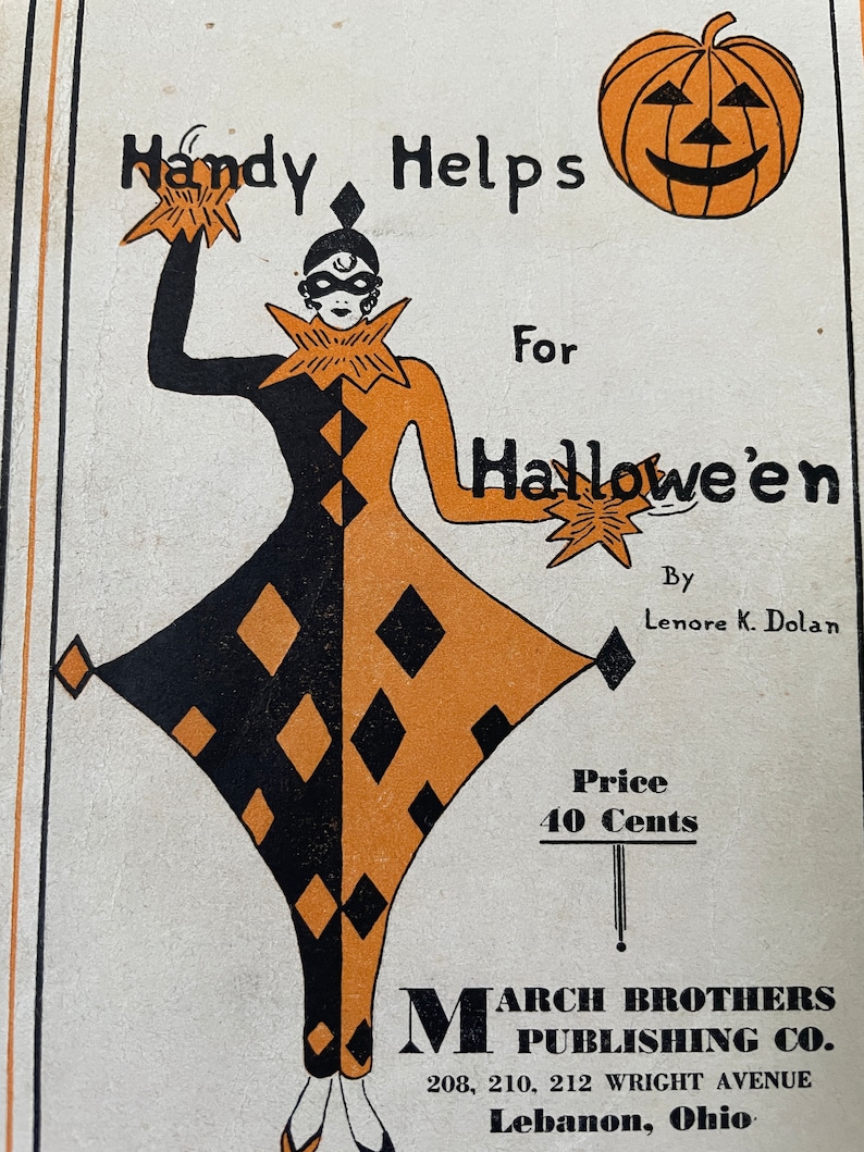 May include: A black and orange illustration of a jester holding stars. The jester is wearing a black mask and a black and orange diamond patterned costume. The text "Handy Helps For Hallowe'en" is written above the jester. The text "By Lenore K. Dolan" is written below the jester. The text "Price 40 Cents" is written below the text "By Lenore K. Dolan". The text "MARCH BROTHERS PUBLISHING CO. 208, 210, 212 WRIGHT AVENUE Lebanon, Ohio" is written below the text "Price 40 Cents".
