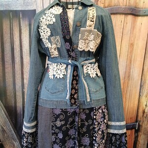 May include: A denim jacket with lace and fabric patches, a tie belt, and a patchwork skirt. The jacket has white lace accents and the word "Blanc" on a patch. The skirt features floral and patterned fabrics.