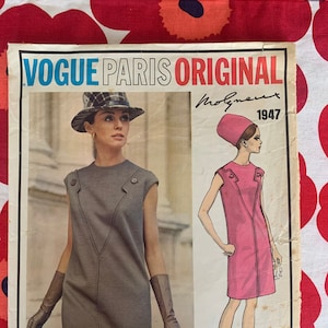Puede incluir: Patrón de costura Vogue Paris Original Molyneux 1947 con dos mujeres vistiendo vestidos. La mujer de la izquierda lleva un vestido gris con un sombrero negro y guantes. La mujer de la derecha lleva un vestido rosa con un sombrero rosa.