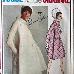 Könnte beinhalten: Ein Vogue Paris Original Schnittmusterumschlag, Nummer 1712 von Pierre Cardin. Die Vorderseite zeigt ein Foto einer Person in einem weißen Mantel und eine Illustration einer Person in einem rosa gesteppten Mantel mit Rautenmuster.