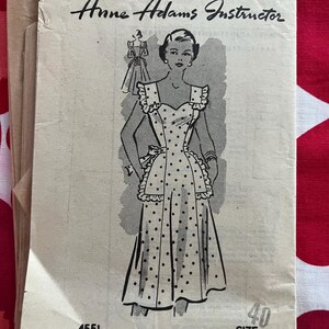 May include: Vintage sewing pattern titled "Anne Adams Instructor." The pattern features an illustration of a woman in a polka dot apron with ruffle details. The pattern number is 4551, and the size is 40.