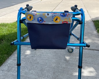 May include: A blue walker with a black fabric bag attached. The bag has a colorful monster print on the top edge.