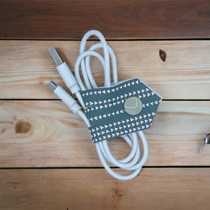 May include: White cable with two USB ends, organized with a gray fabric cable organizer with a white triangle pattern.