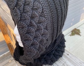 May include: A black crocheted hooded cowl with a textured, scale-like pattern.