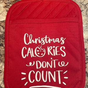 May include: Red quilted oven mitt with white text that reads "Christmas Calories Don't Count".