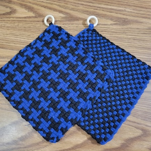 May include: Two blue and black woven pot holders with white loops. The pot holders are made of a thick, textured fabric.