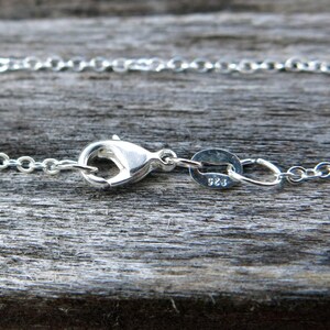May include: Silver chain necklace with a lobster clasp and a small oval tag with the number 925 stamped on it.