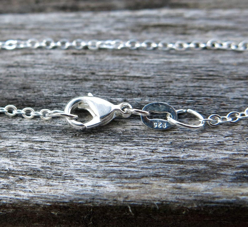 May include: Silver chain necklace with a lobster clasp and a small oval tag with the number 925 stamped on it.