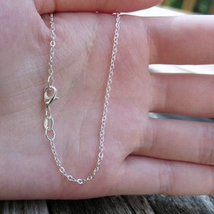 May include: A silver chain necklace with a lobster clasp.
