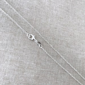 May include: A silver chain necklace with a lobster clasp fastening. The chain is delicate and has a fine, rounded link design.