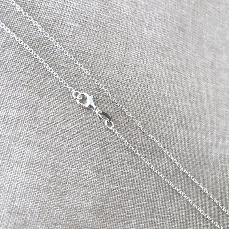May include: A silver chain necklace with a lobster clasp fastening. The chain is delicate and has a fine, rounded link design.