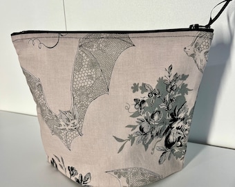 Flying Bats Zipper Pouch • Happy Bats with Lacy Wings fly among Black Flowers and Gray Spider Webs on Light Dusty Mauve Fabric • Whimsicalli