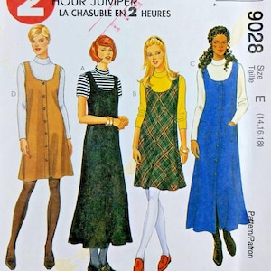 May include: A McCall's 9028 sewing pattern envelope for a jumper dress. The cover features illustrations of four variations of the jumper in different lengths and fabrics, including solid tan, black, green plaid, and blue, worn over various long-sleeve tops.
