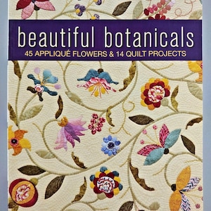 May include: A book titled Beautiful Botanicals: 45 Appliqué Flowers & 14 Quilt Projects by Deborah Kemball. The cover features a cream-colored quilt background with various colorful fabric appliqué flowers and swirling vine patterns.