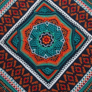Puede incluir: Una manta de ganchillo con un patrón geométrico en tonos turquesa, naranja y marrón. El centro de la manta presenta un gran diseño de mandala intrincado.