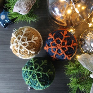 May include: Four crocheted Christmas ornaments with snowflake designs. The ornaments are in shades of brown, green, blue, and orange.