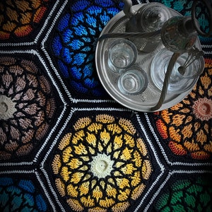 May include: A silver tray with a teapot, a coffee pot, and six glasses on a colorful crocheted hexagon pattern rug.