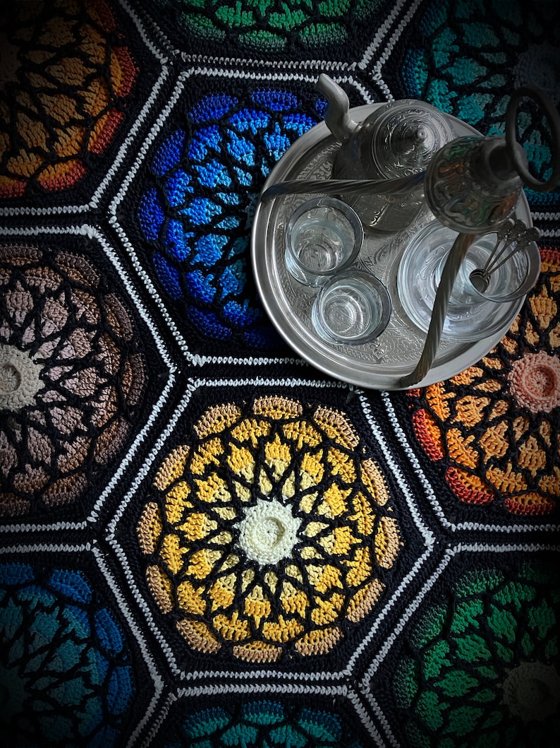 May include: A silver tray with a teapot, a coffee pot, and six glasses on a colorful crocheted hexagon pattern rug.