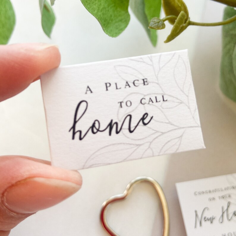 Op de afbeelding: Een witte kaart met een bladontwerp en de tekst "A place to call home" in zwarte letters.