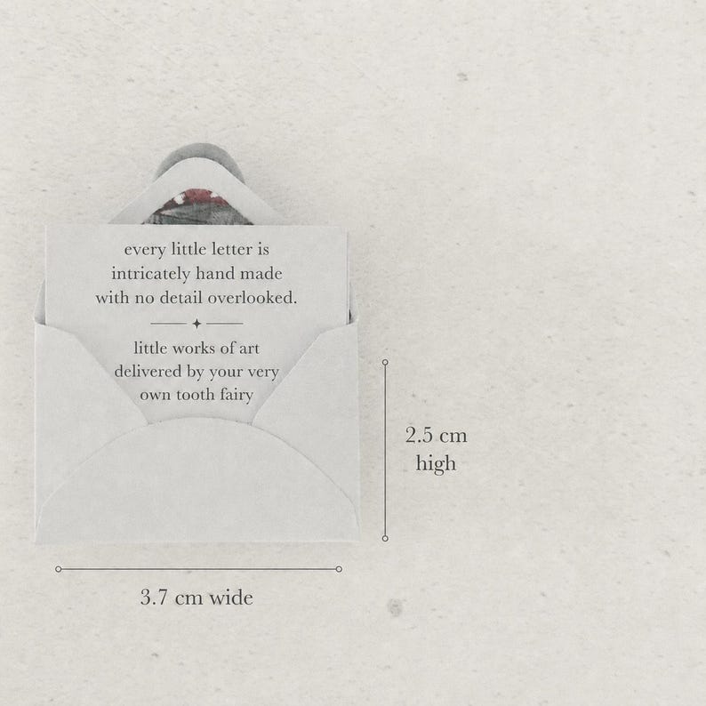 K&ouml;nnte beinhalten: Ein kleiner cremefarbener Umschlag mit einer Karte, auf der steht: every little letter is intricately hand made with no detail overlooked. little works of art delivered by your very own tooth fairy. Der Umschlag ist 3,7 cm breit und 2,5 cm hoch.