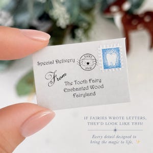 K&ouml;nnte beinhalten: Ein kleiner wei&szlig;er Briefumschlag mit dem Text Special Delivery, From The Tooth Fairy, Enchanted Wood, Fairyland. Auf der Vorderseite befinden sich ein kreisf&ouml;rmiger Poststempel und eine blaue Briefmarke mit einer wei&szlig;en Zahnillustration.
