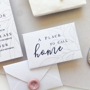 Op de afbeelding: Een witte kaart met een grijs bloemenpatroon en de tekst "A place to call home" in zwarte letters.