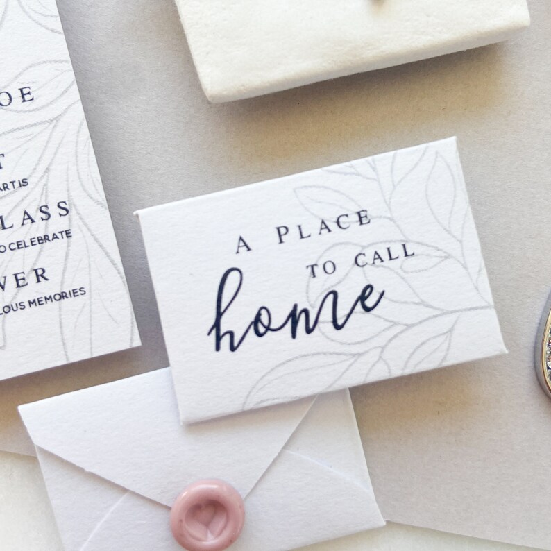 Op de afbeelding: Een witte kaart met een grijs bloemenpatroon en de tekst "A place to call home" in zwarte letters.
