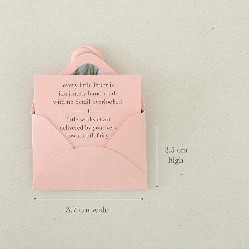 以下が含まれることがあります： 「every little letter is intricately hand made with no detail overlooked. little works of art delivered by your very own tooth fairy.」と書かれたメモが入った、淡いピンク色の小さな封筒。幅3.7cm、高さ2.5cmです。