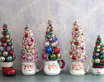 Árvore de Natal artesanal decorada em estilo vintage, feita com escovas de garrafa, em caneca de cerâmica rosa e vermelha.