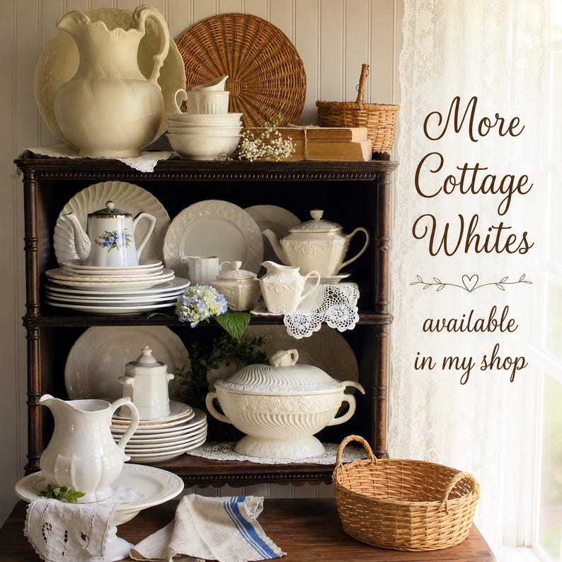 May include: A dark wooden hutch filled with cream-colored ceramic dinnerware, including teapots, plates, bowls, and a lidded tureen. The text "More Cottage Whites available in my shop" is visible on the right. Wicker baskets and linens are present.