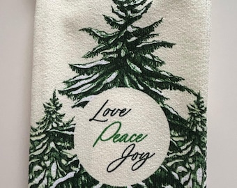 May include: White and green Christmas-themed kitchen towel with a matching pot holder. The towel features green pine trees and the words "Love, Peace, Joy" in a circular design. The pot holder has the word "Love" printed on it.
