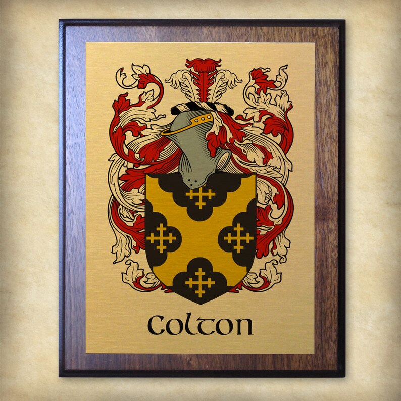 K&ouml;nnte beinhalten: Eine goldene Plakette mit einem braunen Holzrahmen zeigt ein Wappen mit einem gelben Schild mit schwarzen Kreuzen und einem Helm mit einer rot-wei&szlig;en Feder. Der Text "Colton" ist unter dem Wappen gedruckt.