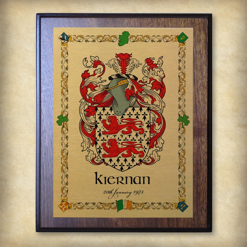 K&ouml;nnte beinhalten: Eine goldene Plakette mit einem braunen Holzrahmen zeigt ein Wappen mit einem Helmzier, einem Schild und zwei roten L&ouml;wen. Der Text "Kieran 20th January 1973" befindet sich unter dem Wappen.