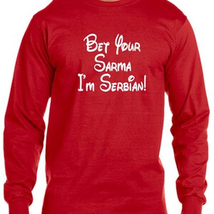 May include: Red long-sleeve t-shirt with white text that reads "Bet your sarma I'm Serbian!" in a stylized font.