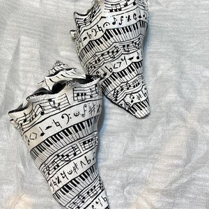 May include: Two white seashells with black musical notes and piano keys painted on them.