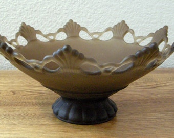 May include: A decorative brown glass bowl with a scalloped rim and a pedestal base. The bowl has a frosted appearance and is designed with a shell-like pattern around the edges. The bowl is approximately 10 inches in diameter.