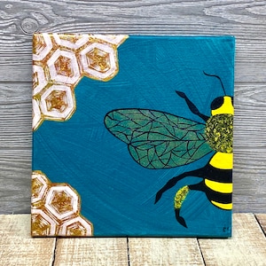 May include: A painting of a bee with yellow and black stripes on a teal background. The bee has a green and black patterned wing. The background also has a honeycomb pattern in gold and white.