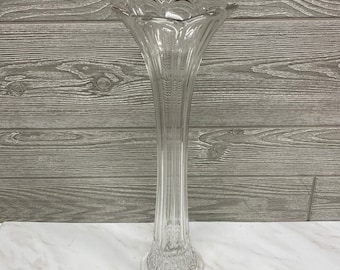 May include: A clear glass vase with a textured surface and a flared opening. The vase is tall and slender, with a classic design.