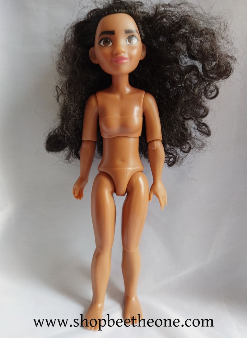 Pode incluir: Uma boneca de pl&aacute;stico nua com pele marrom, cabelo preto encaracolado e olhos castanhos. A boneca est&aacute; em p&eacute; com os bra&ccedil;os ao lado do corpo.
