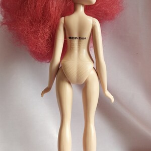 May include: A doll with red hair, blue eyes and a nude swimsuit. The doll has a number printed on its back: #B5285 53101.