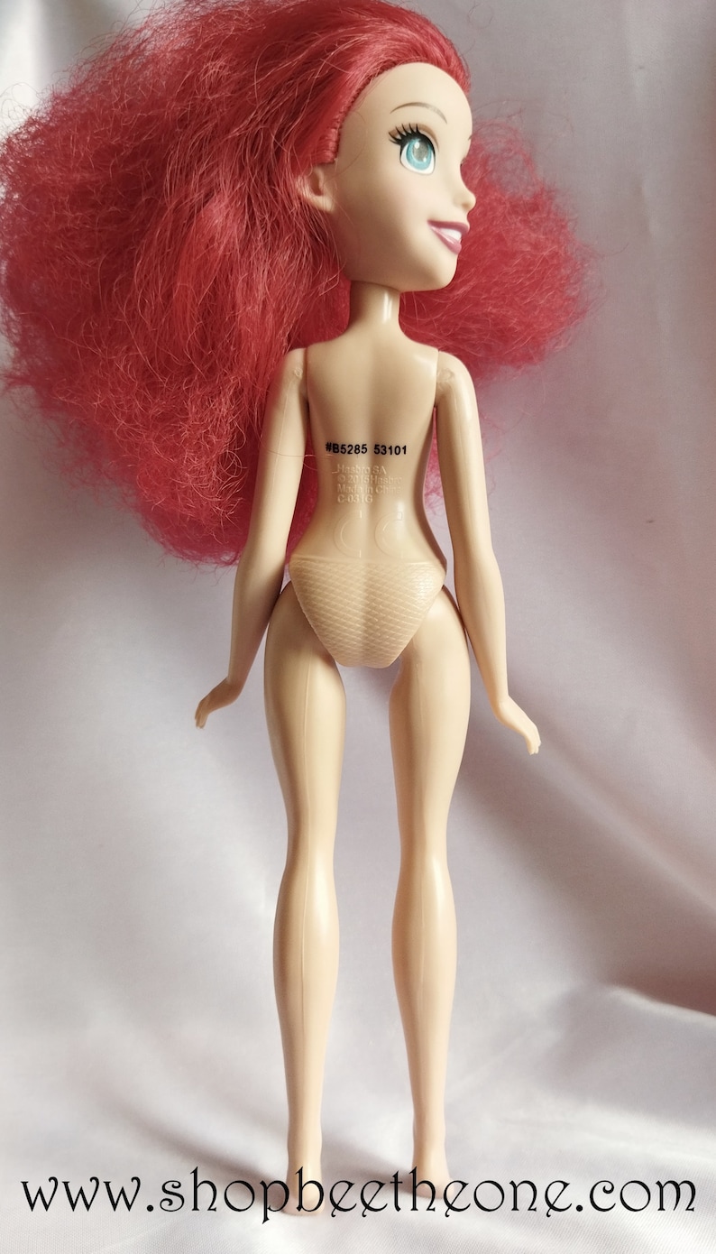 May include: A doll with red hair, blue eyes and a nude swimsuit. The doll has a number printed on its back: #B5285 53101.