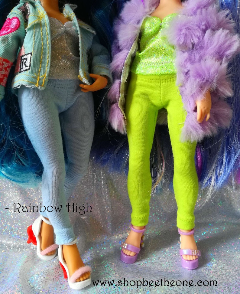 May include: Two dolls wearing colorful outfits and platform shoes. The doll on the left is wearing a blue denim jacket with a heart patch, a silver glitter top, and light blue leggings. The doll on the right is wearing a purple furry jacket, a green glitter top, and bright green leggings. Both dolls are wearing platform shoes with a rainbow design.