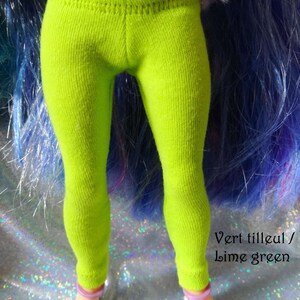 May include: Lime green leggings for a doll. The leggings are made of a soft, stretchy fabric and have a ribbed texture. The text "Vert tilleul / Lime green" is visible at the bottom of the image.
