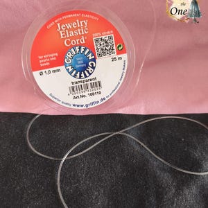 Op de afbeelding: Een spoel Griffin sieradenelastiek met een transparante afwerking. Het etiket geeft een diameter van 1,0 mm, een lengte van 25 m en 200% rek aan. De spoel is voorzien van een QR-code, een streepjescode en de tekst Jewelry Elastic Cord.