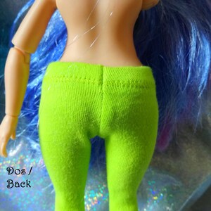 May include: Back view of a doll wearing bright green leggings. The doll has long blue hair with purple highlights. The text "Dos / Back" and "www.shopbeethetone.com" is visible in the image.