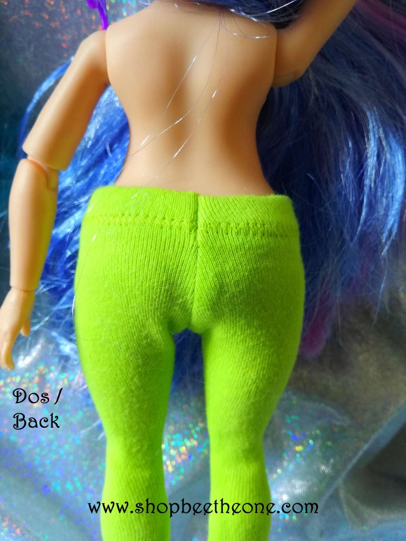 May include: Back view of a doll wearing bright green leggings. The doll has long blue hair with purple highlights. The text "Dos / Back" and "www.shopbeethetone.com" is visible in the image.
