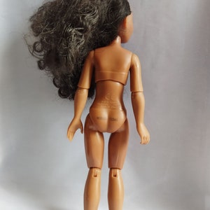 Pode incluir: Uma boneca de pl&aacute;stico marrom com cabelo longo e preto encaracolado. A boneca est&aacute; vestindo um mai&ocirc; cor de pele e tem um pequeno adesivo branco nas costas com o texto "&copy;2018 HASBRO INC. MADE IN CHINA.  B0316-72341".