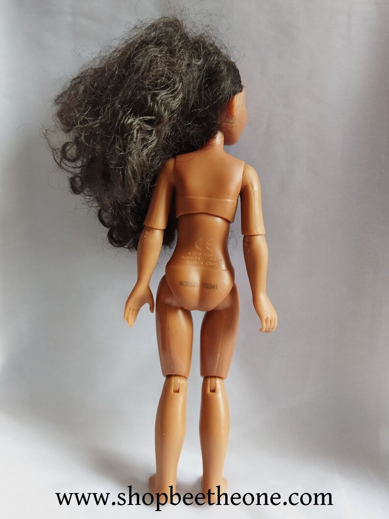 Pode incluir: Uma boneca de pl&aacute;stico marrom com cabelo longo e preto encaracolado. A boneca est&aacute; vestindo um mai&ocirc; cor de pele e tem um pequeno adesivo branco nas costas com o texto "&copy;2018 HASBRO INC. MADE IN CHINA.  B0316-72341".