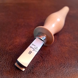 Puede incluir: Una herramienta para tallar madera con un mango de madera marrón claro y una hoja plateada. La hoja tiene el texto "Starko Tools 8" impreso. La herramienta está diseñada para proyectos detallados de carpintería y tallado.